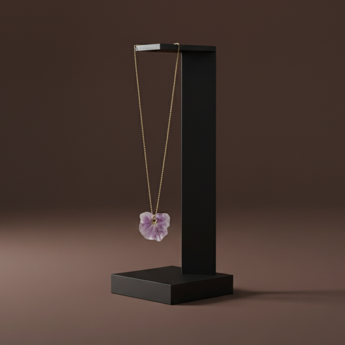 Necklace with a floral pendant on a black stand against a brown background, featuring the Natura brand.